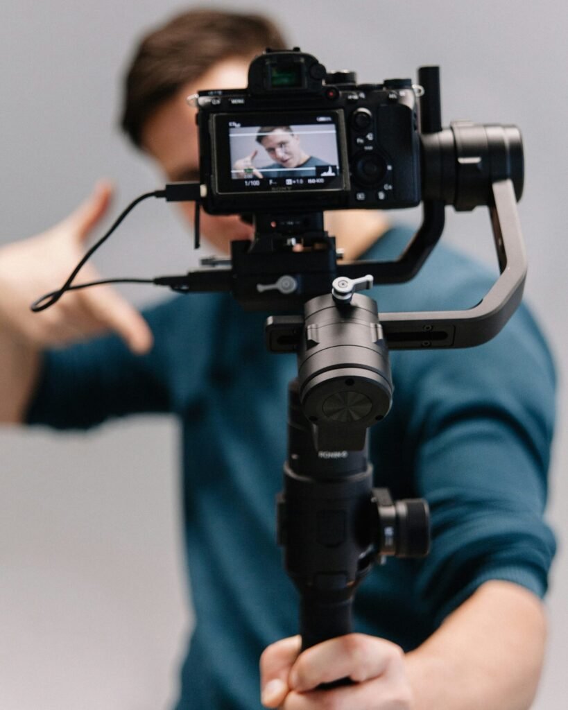 man holding black DSLR camera with stabilizer